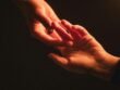 Two hands gently reaching toward each other in warm light, symbolising connection and emotional support.