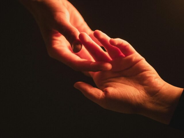 Two hands gently reaching toward each other in warm light, symbolising connection and emotional support.