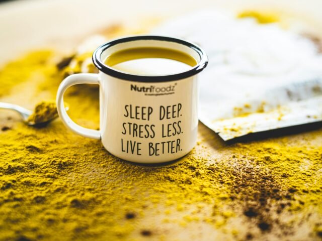 White enamel mug with turmeric powder and wellness message: “Sleep Deep. Stress Less. Live Better. Symbolises relaxation and better sleep through reflexology.