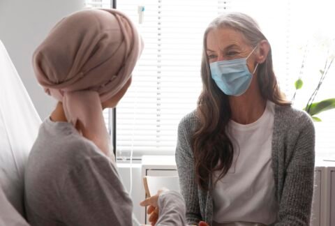 A practitioner offering calm, supportive communication with a client during cancer treatment, reflecting compassionate care and clear boundaries.
